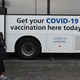 People receiving their covid-19 vaccine or booster at a NHS (National Health Service) bus outside an Asda Supermarket in the town of Farnworth, near Manchester in north-west England on December 20, 2021.